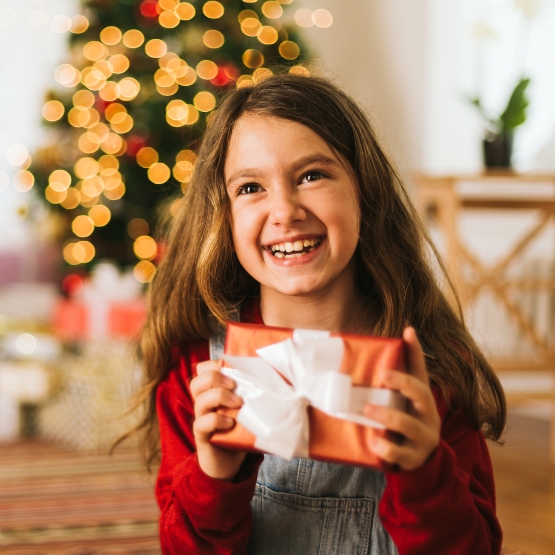 Child holding present with Christmas tree in background