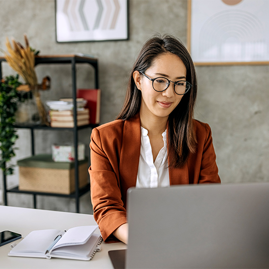 woman with glasses typing on computer