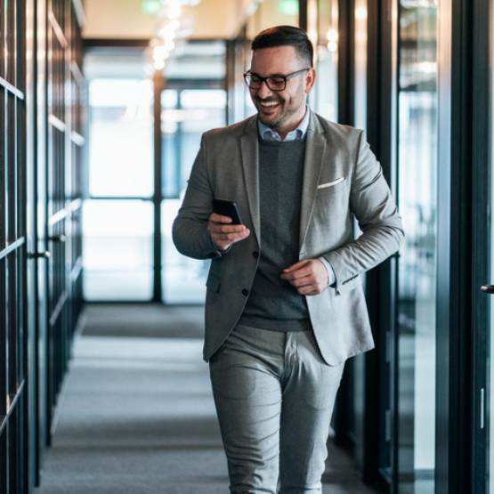 Smiling person walking through hallway on cell phone