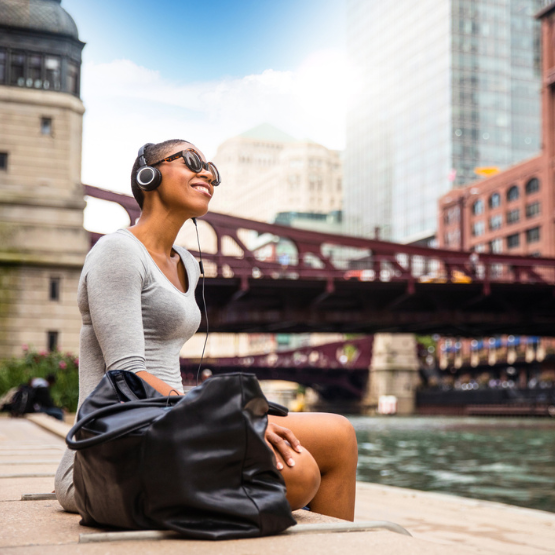 Woman with headphones sitting outside in the city