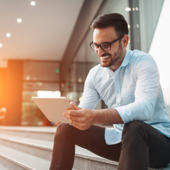 Person sitting outside office steps using tablet