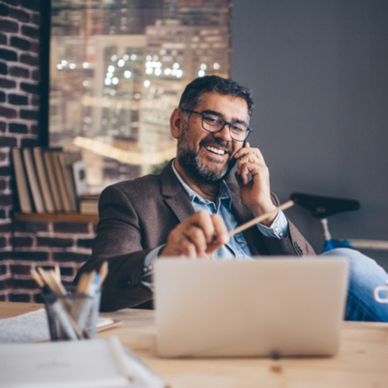 Businessman talking on cell phone and looking at laptop