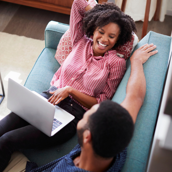 Couple laughing on couch and looking at computer