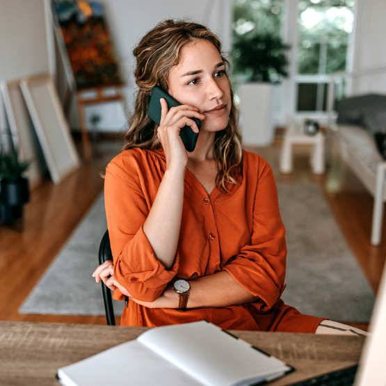 Woman sitting in her home and talking on her cell phone