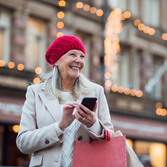 Woman outside on street with holiday lights in background