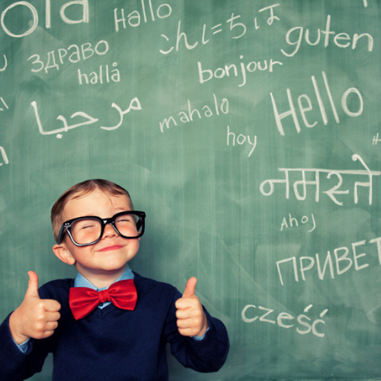 Young student giving thumbs up standing in front of chalkboard