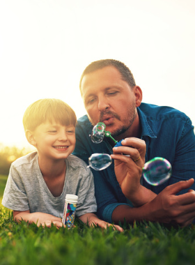 Father and son blowing bubbles outside