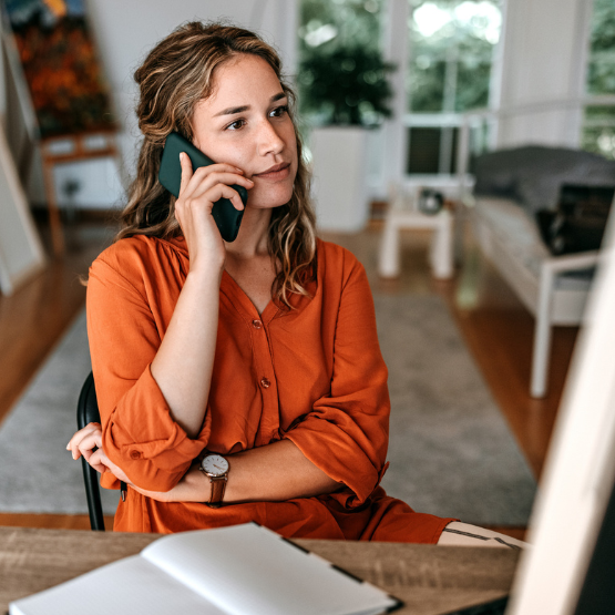 Woman sitting in her home and talking on her cell phone