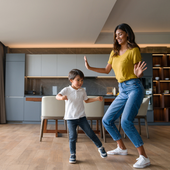 Mom and young son dancing in house