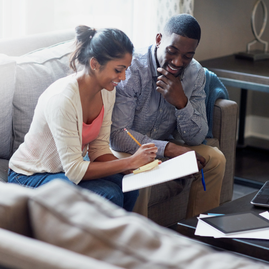 Couple sitting on couch writing in a notebook